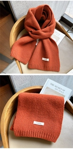 Detailed view of caramel wool scarf showing 100% wool label and soft ribbed knit texture