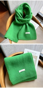 Close-up of bright green knitted wool scarf showing rib edge and 100% wool label