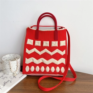 Macro detail of red knitted mobile phone bag with geometric patterns and shoulder strap