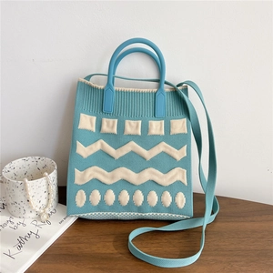 Close-up of blue and white knitted mini tote bag with geometric patterns on wood surface