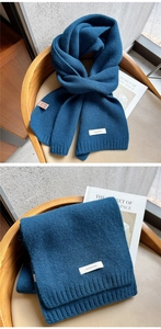 Detail of dark blue 100% wool knitted scarf with ribbed texture and fabric care label