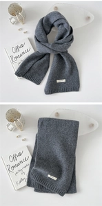 Close-up of gray 100% wool knitted scarf showing texture and premium brand label