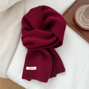 Detail of burgundy 100% wool scarf showing high-quality knit texture and white label