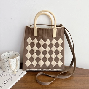 Detail of checkered knit tote bag with round handle and brown strap on a table