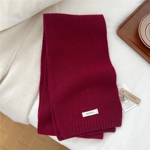 Detail of burgundy wool scarf with 100% wool label and cedar wood mothproof tag