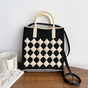 Detail of checkered knit crossbody bag with top handle and shoulder strap in black and white