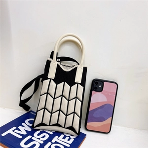 Close-up of knit crossbody phone bag with black and white geometric pattern and handle