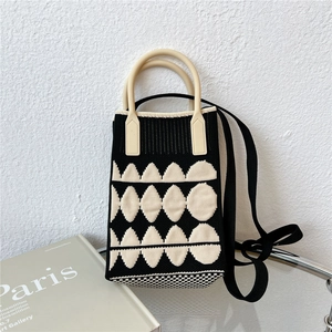 Close-up of a mini knit phone bag with geometric patterns and beige curved handles