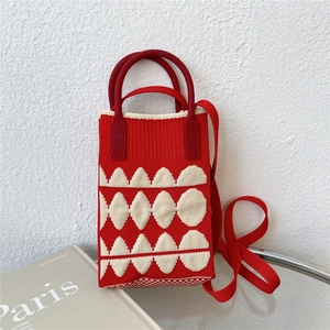 Detail of red and white knit phone bag with geometric pattern and silicone handle