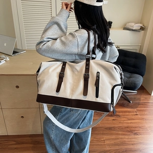 Large beige canvas duffle bag with brown straps for travel and gym use on model