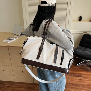 Large cream canvas travel bag with brown leather trim shown in a stylish lifestyle setting