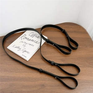 Adjustable black leather shoulder straps with silver buckles on a wooden table