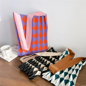 Trois sacs cabas en maille à carreaux avec design plissé sur une table en bois