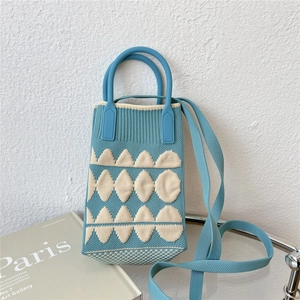 Detail of blue knitted mini crossbody bag with beige geometric patterns and round handles
