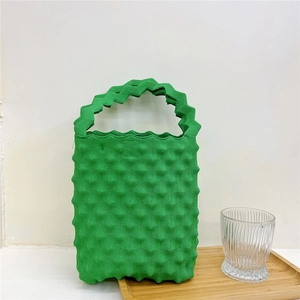 Close-up of bright green handbag with 3D bubble texture and zigzag handle detail