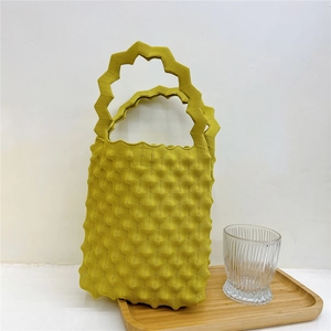 Detailed view of yellow knitted handbag with wavy texture and zigzag handle design