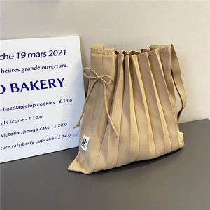Close-up of pleated knit shoulder bag texture with ribbon tie and October fabric label