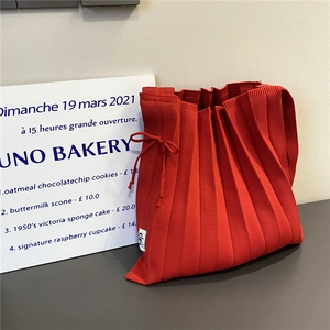 Large red pleated knit shoulder bag with drawstring detail and minimalist aesthetic