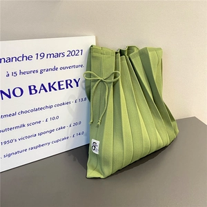Detail of avocado green pleated knit tote bag with bow detail and brand tag