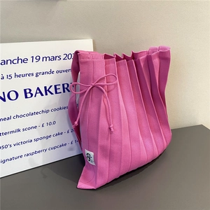 Detailed texture of pink pleated knit tote bag with decorative bow and October label