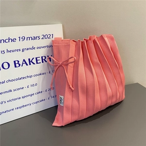 Detailed macro view of pink pleated knit bag with delicate side ribbon bow detail