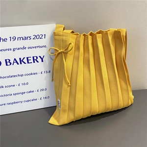 Macro shot of bright yellow knitted tote bag with pleated texture and bow detail