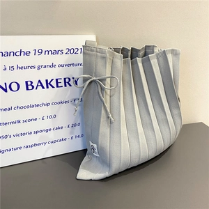 Detail of light gray pleated knit tote bag with side bow and brand label detail