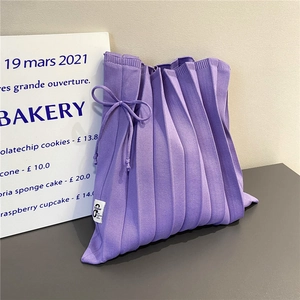 Close-up of purple pleated knit bag showing stretch fabric texture and ribbon bow detail