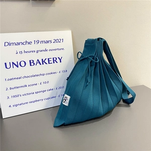 Detail of peacock blue pleated knit bag with drawstring closure and October tag