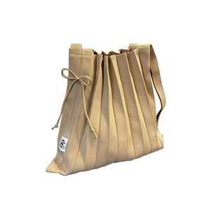 Minimalist beige pleated knitted shoulder bag with side bow detail and branded tag