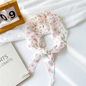 Détail d'un foulard en tulle à fleurs roses noué en nœud avec calendrier et livre d'art