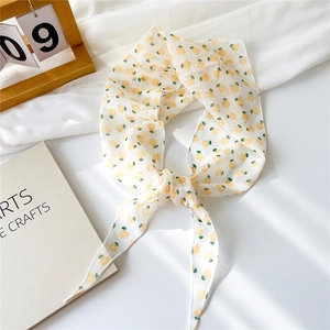 Détail d'un foulard en tulle en forme de losange avec motifs floraux jaunes
