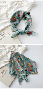 Detailed close-up of grey-green floral cotton linen scarf with elegant white hem stitching