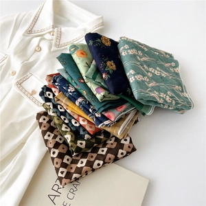 Assorted cotton linen square scarves with floral and polka dot prints stacked on a shirt