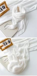 Close-up of pleated white cotton scarf with wavy edges and soft lightweight texture