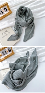 Detail of grey pleated scarf featuring fine accordion folds and wavy hem edges