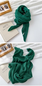 Detail of dark green pleated cotton-linen scarf with fine accordion pleats and soft texture