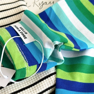 Detail of striped knitted sleeve cuff featuring a white logo label and waffle texture