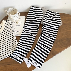 Detail of knitted arm sleeves with black and white stripes and a branded woven label
