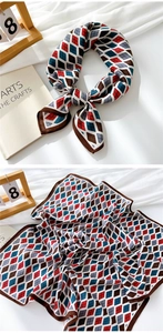 Close-up of argyle pattern silk scarf with red and blue tones on a textured white fabric