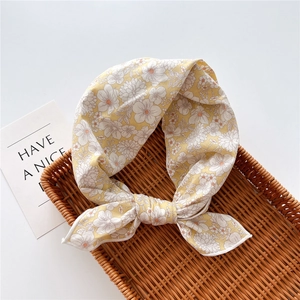 Dettaglio di un foulard di cotone a fiori gialli con motivi bianchi e trama in tessuto