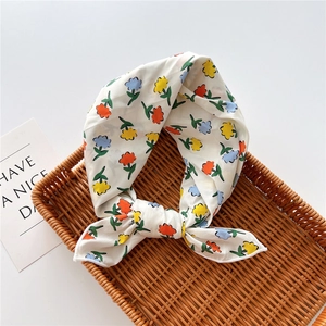 Dettaglio di un foulard in lino di cotone a fiori annodato su un vassoio di vimini