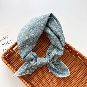Dettaglio di un foulard in cotone e lino azzurro a fiori annodato in un cesto intrecciato