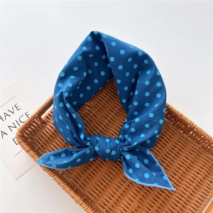 Navy blue polka dot cotton linen neck scarf displayed on a woven tray