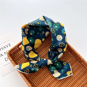Detailed close-up of dark blue cotton linen scarf with lemon and flower prints in a basket