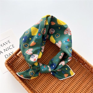Detail view of green cotton-linen scarf with colorful cartoon floral and heart patterns