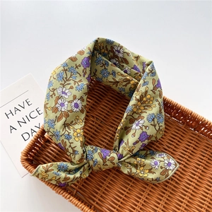 Dettaglio del foulard in cotone e lino con piccoli fiori su sfondo verde salvia