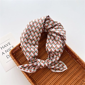Close-up of geometric pattern silk scarf knotted in a woven basket on a white base