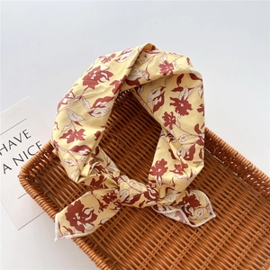 Dettaglio del foulard in cotone e lino giallo zenzero con motivi floreali rossi