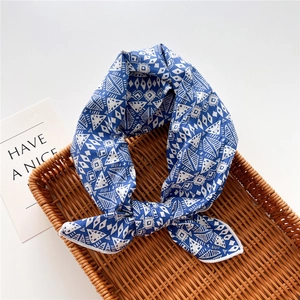 Detail of blue geometric print cotton-linen small scarf styled as a bow in a basket